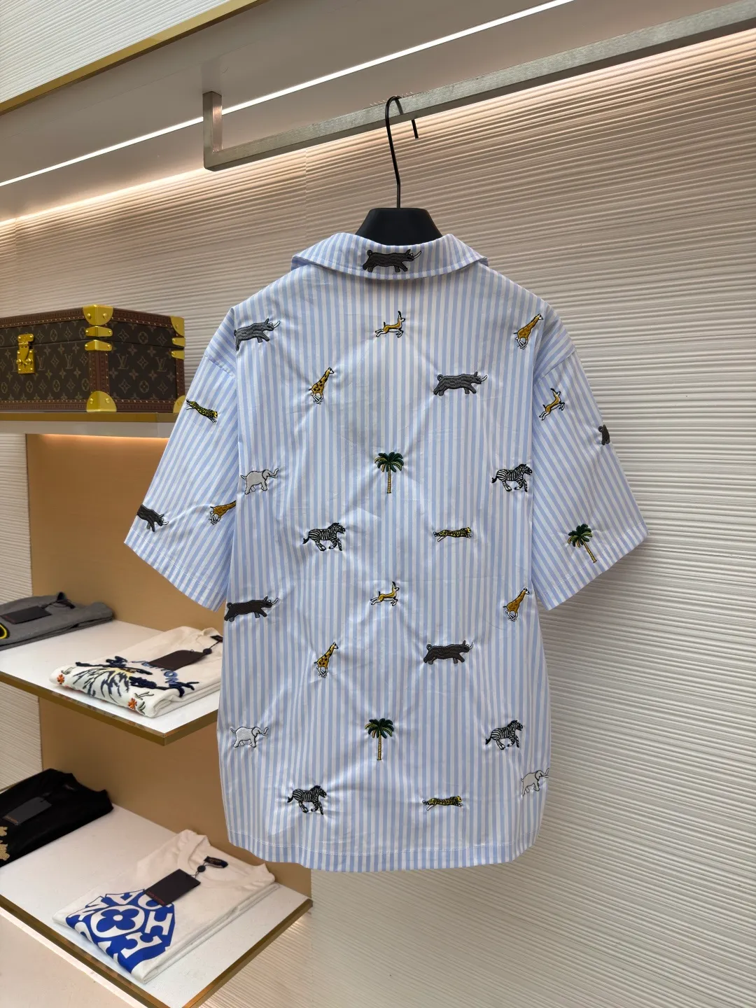 LOUIS VUITTON nostalgic style embroidered striped short-sleeved shirt with animals and plants ●Original version: Purchased and developed by 16815 ●Item number: 1682514-A65 ●Fabric: cotton fabric ●Technology: embroidery production ●Color: blue ●Version: fitted version ●Weight: about 220 grams ●Size: S-M-L-XL ●Description: This LOUIS VUITTON striped animal embroidery short-sleeved shirt is made of high-count pure cotton poplin fabric. After pre-washing process, it feels smooth and breathable. It has both drape and stiffness, and is not easy to wrinkle and deform. The blue and white vertical stripes on the body are woven with yarn-dyed technology, and the texture is clear and does not fade. The animal and coconut tree patterns are presented with sophisticated embroidery technology. The embroidery threads are full of color and the stitches are dense. The patterns are three-dimensional and vivid, forming a rich visual hierarchy with the stripe base. The shirt has a Cuban collar style, with smooth necklines, custom mother-of-pearl buttons at the placket, and a warm texture. The overall shape is loose, the shoulder joints are straight and fine, the cuffs are cuffed with exquisite craftsmanship, custom accessories and three logos are complete, and the details are full of luxury craftsmanship. It is suitable for casual vacations and daily outings, etc. The overall wiring is straight and delicate, the fabric is comfortable and soft, and the color is consistent without color difference. It can be matched with the same style to create a fashionable look and control various occasions. Customized accessories, complete with three standards, same style for men and women!